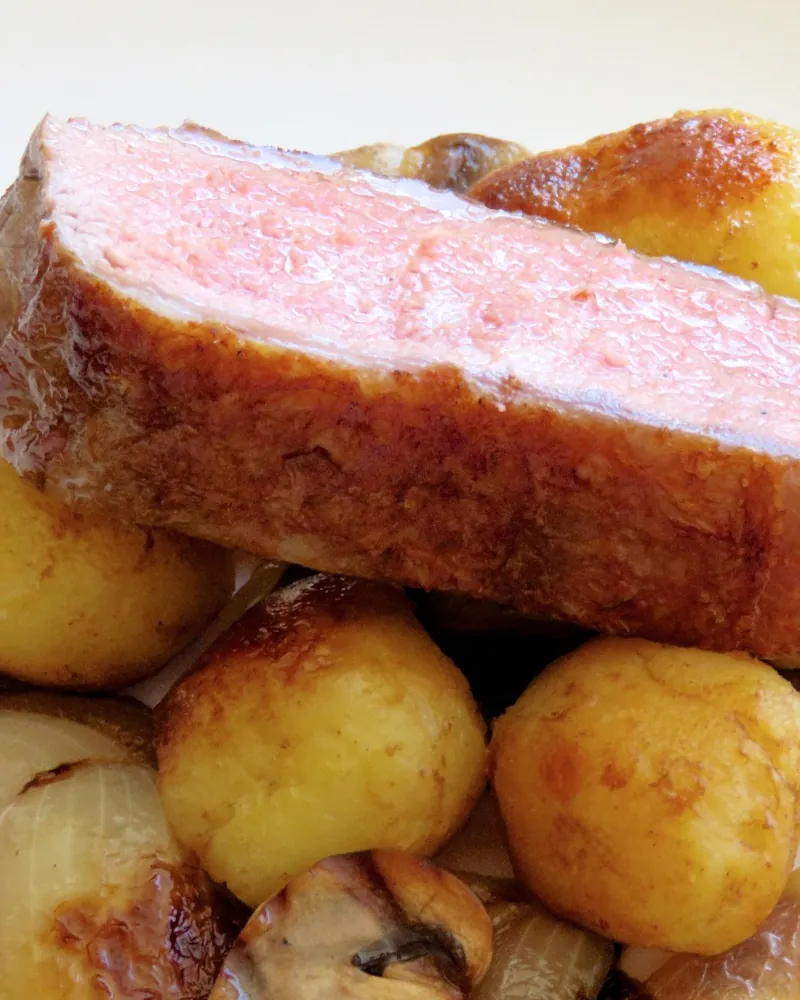 Corte de vitelo rosado grelhado com batatas, cogumelos e cebolas